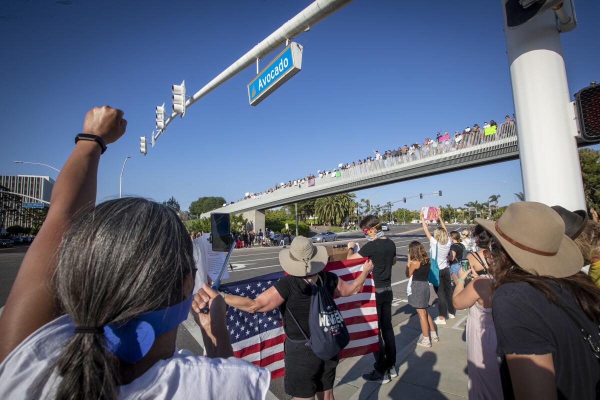 Prostesters rally at the Newport Beach Civic Center Park bridge in Newport Beach.