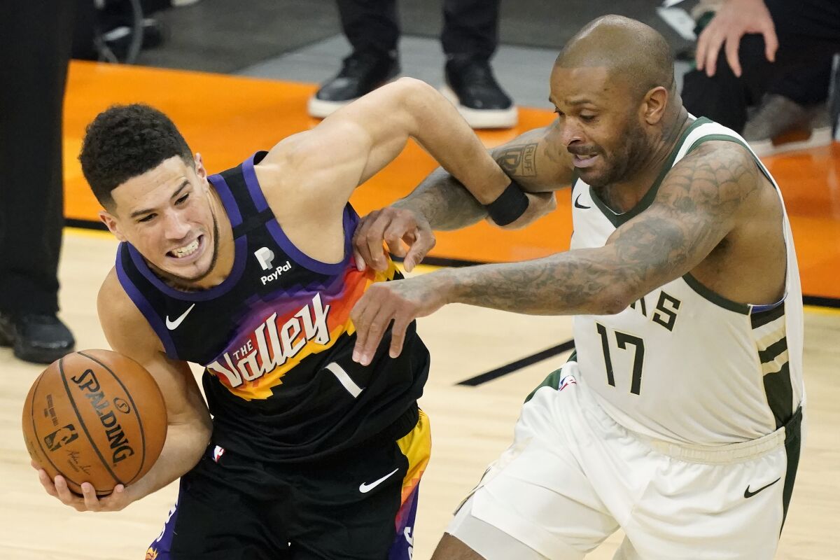Phoenix Suns guard Devin Booker, left, is defended by Milwaukee Bucks forward P.J. Tucker during the first half of Game 5 of basketball's NBA Finals, Saturday, July 17, 2021, in Phoenix. (AP Photo/Matt York)