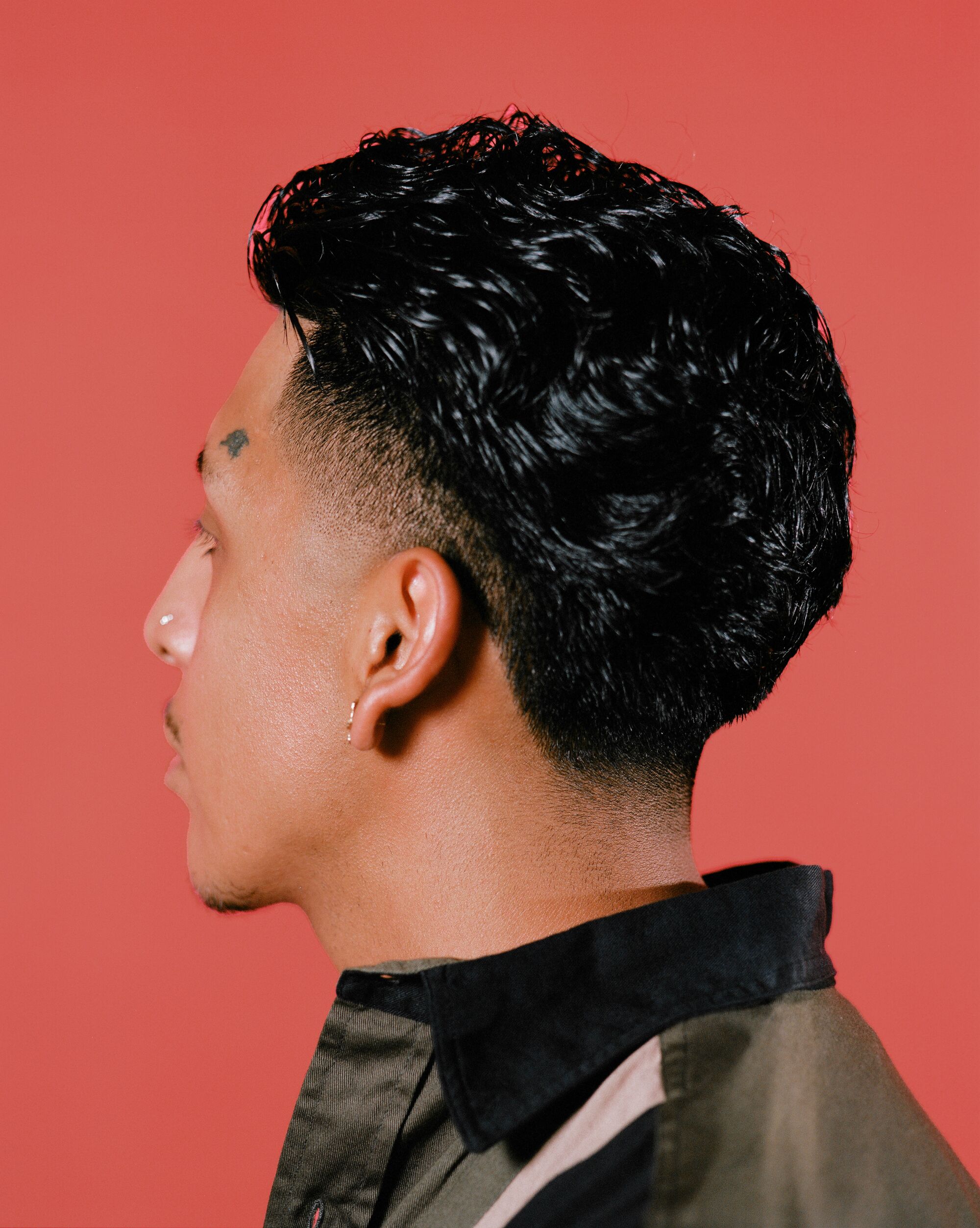 Image of a man looking away from the camera, the side profile of the Edgar haircut in view.
