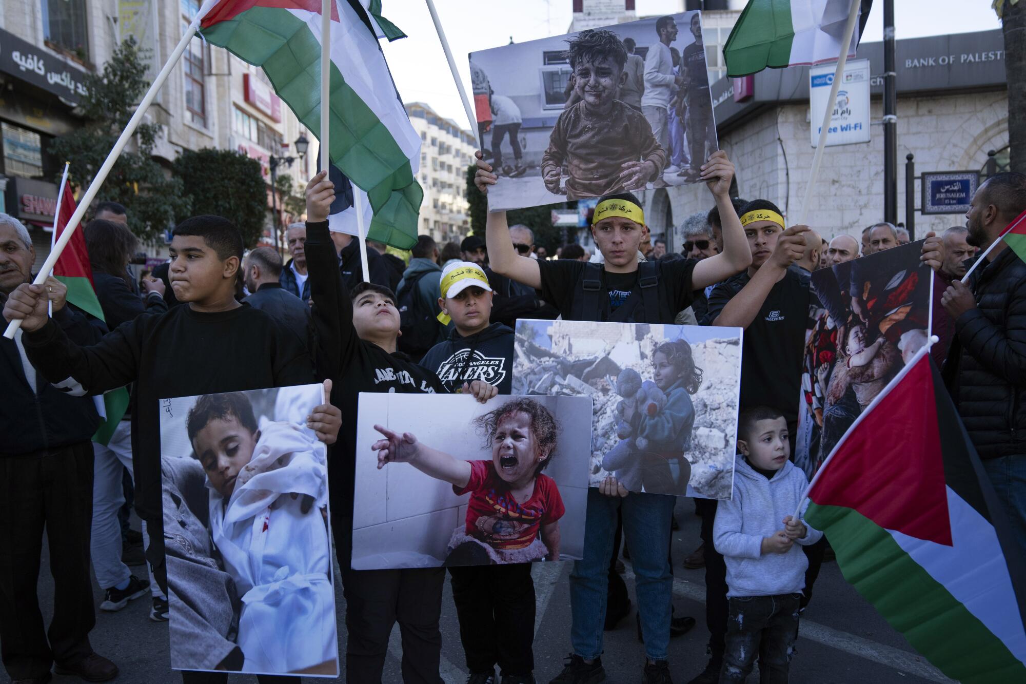 Demonstrators march with posters showing photos of injured or screaming children.