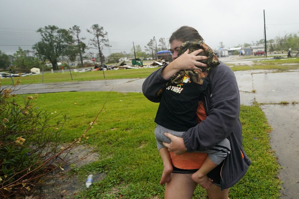 Danielle Fontenot runs to a relative's home in the rain, holding her son.