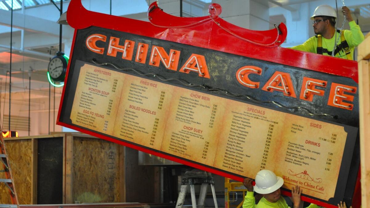 Workers hoist the neon sign above Grand Central Market's China Café, which is getting a makeover after nearly 60 years. (Amy Scattergood / Los Angeles Times)