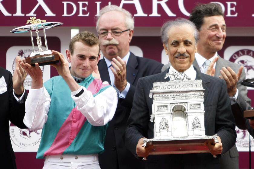 Khalid Abdullah of Saudi Arabia, right, owner of Workforce, ridden by jockey Ryan Lee Moore of Great Britain, left, celebrate with the trophy after winning the Prix de l'Arc de Triomphe, Europe's premier middle-distance horse race, Sunday Oct. 3, 2010 at Longchamp race track in Paris. (AP Photo/Francois Mori)