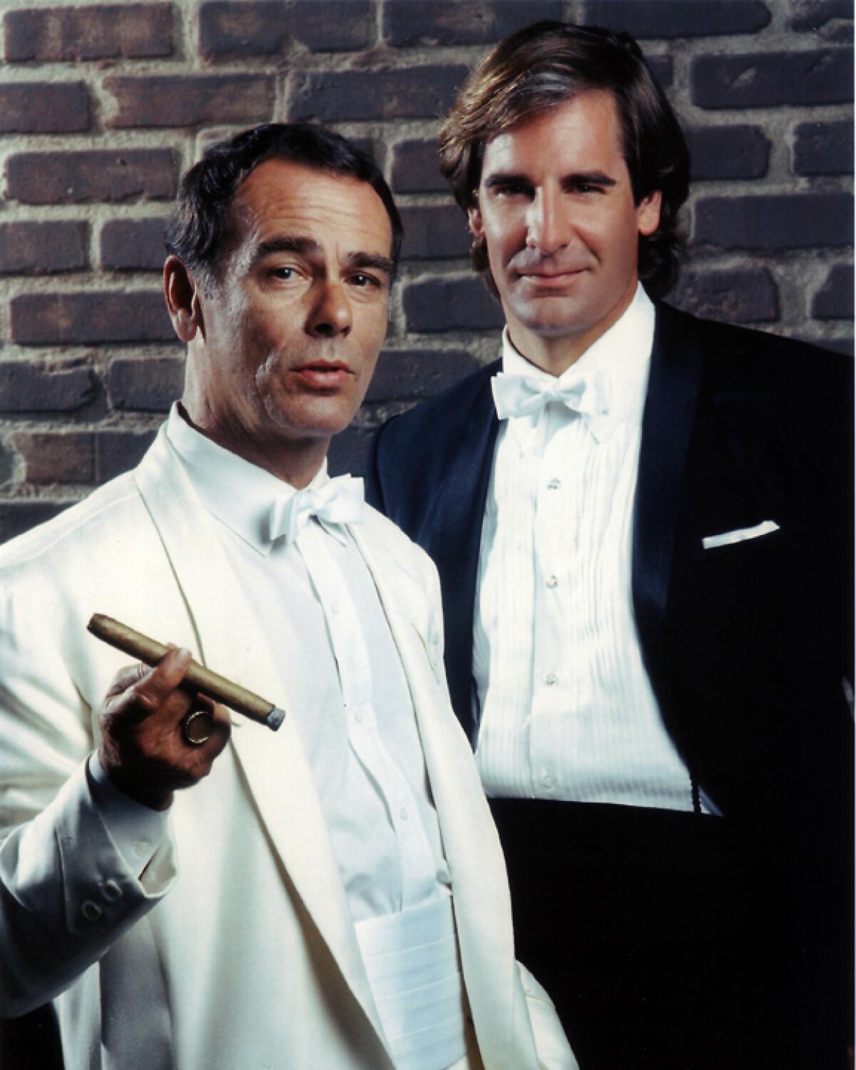 Two men in tuxedos, one holding a cigar