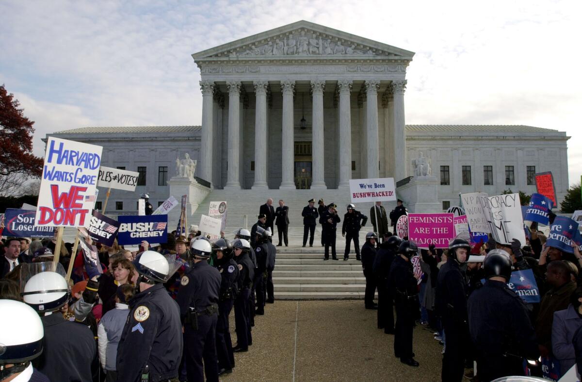 Police officers in riot gear separate the George W. Bush supporters from the Al Gore supporters in front of the Supreme Court on Dec. 1, 2000.