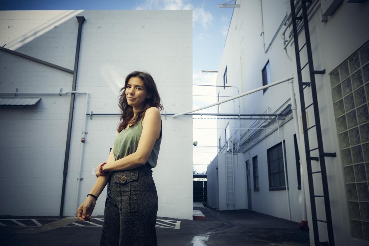 A woman stands amid studio buildings.