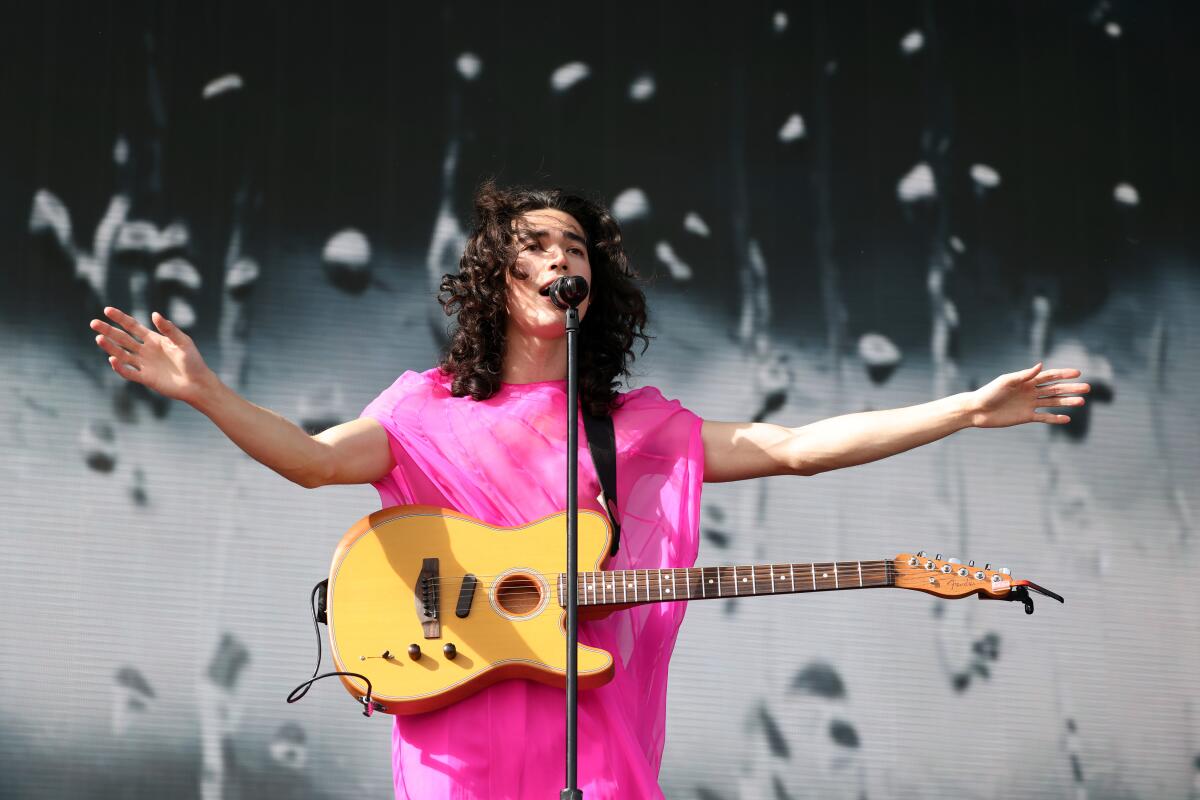 A male singer in a pink dress performs onstage