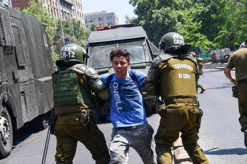 Policías someten a un manifestante en una protesta contra el aumento en la tarifa de transporte, en Santiago.