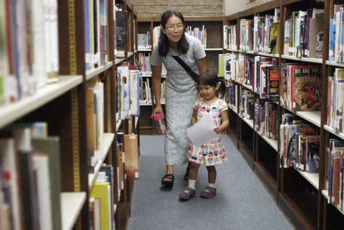 Katsuko Machida, left, and her daughter, Risa, 4, look for another clue during a scavenger hunt that celebrated Los Angeles County Library's 100th anniversary celebration at La Canada Flintridge Library.