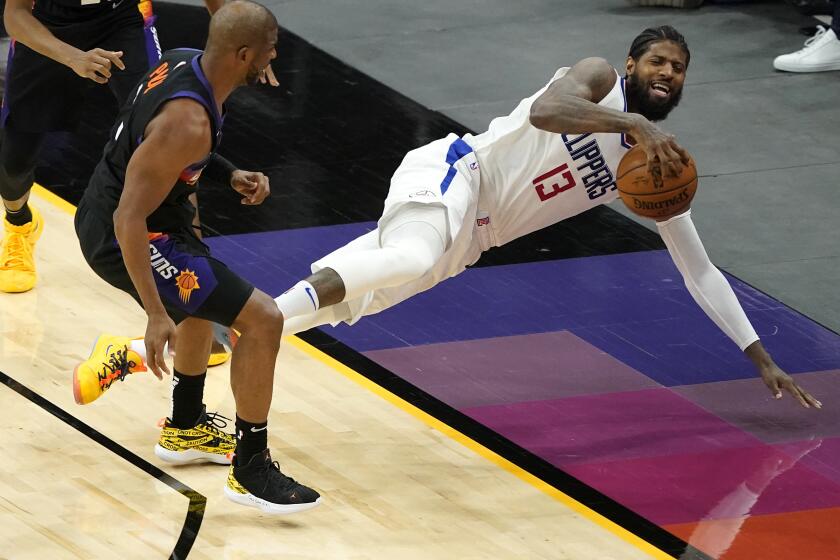 Los Angeles Clippers guard Paul George (13) falls out of bounds after being fouled by Phoenix Suns guard Chris Paul during the second half of an NBA basketball game, Wednesday, April 28, 2021, in Phoenix. (AP Photo/Matt York)