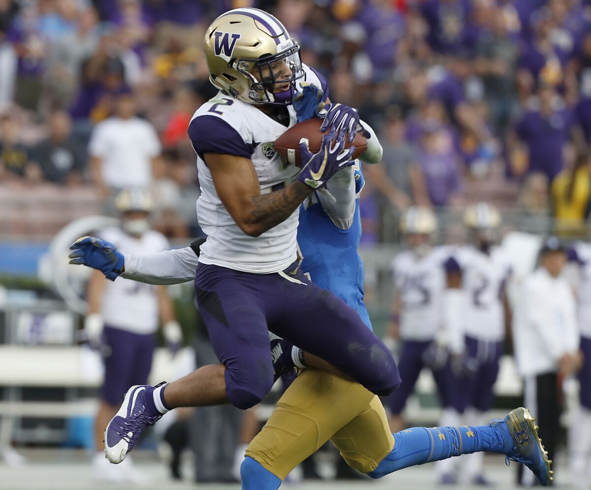 Washington wide receiver Aaron Fuller makes a catch against UCLA defensive back Nate Meadors for a big gain in the second quarter on Saturday at the Rose Bowl.