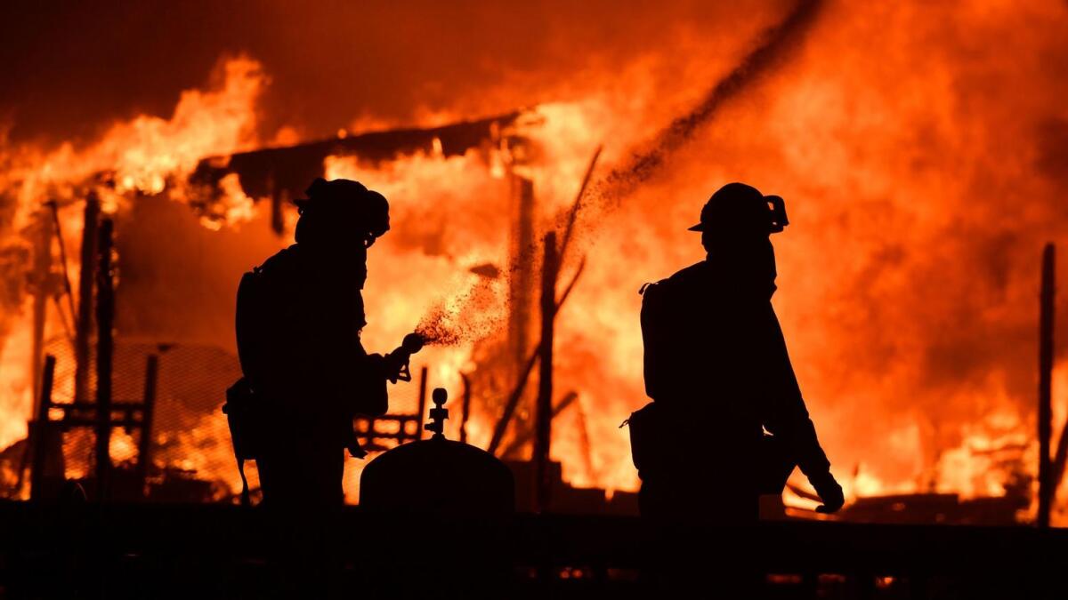 Firefighters douse flames as a home burns in the Napa wine region, as multiple wind-driven fires continue to whip through the region.