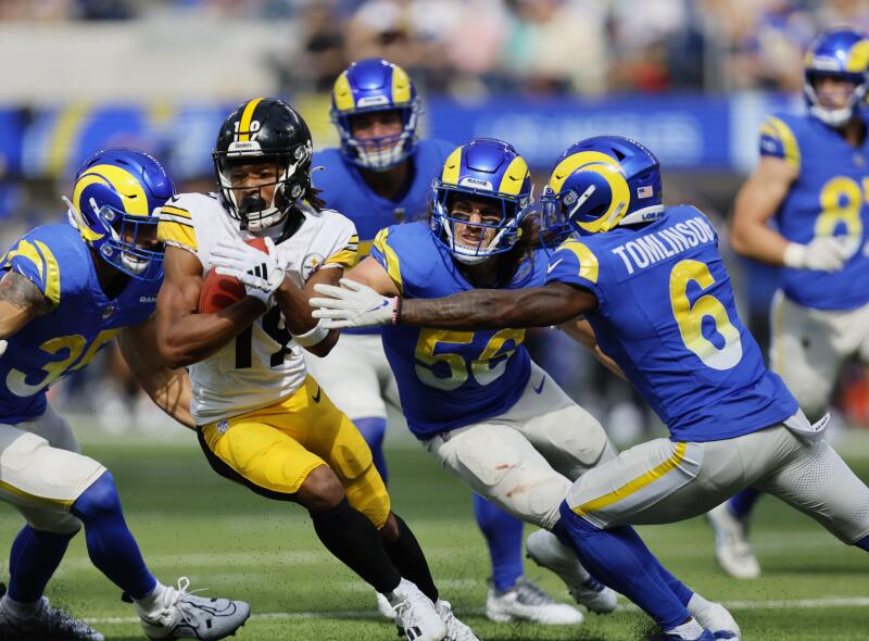 Rams players Jake Hummel, Christian Rozeboom and Tre Tomlinson tackle Pittsburgh Steelers wide receiver Calvin Austin II.