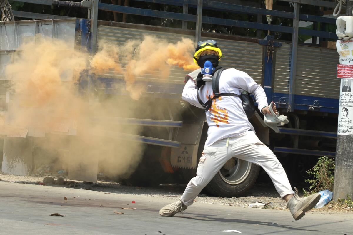 An anti-coup protester throws a smoke bomb against police crackdown at Thaketa township in Yangon, Myanmar, Saturday, March 27, 2021. The head of Myanmar's junta used the occasion of the country's Armed Forces Day to try to justify the overthrow of the elected government of Aung San Suu Kyi, as protesters marked the holiday by calling for even bigger demonstrations. (AP Photo)