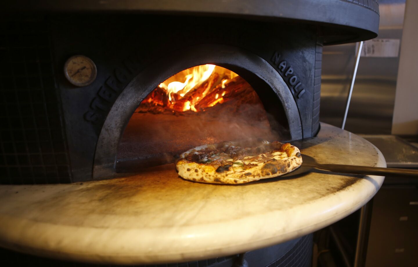 Steam rises from a pizza cooked in a wood oven at Pizzana in Brentwood.