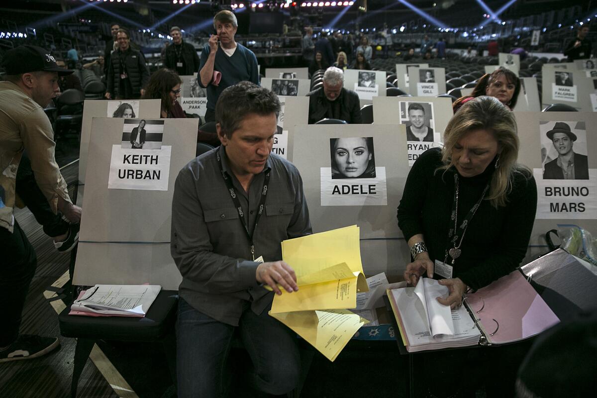 Brian Beacock and Anne Winkowski, who are standing in for Keith Urban and Adele, look over notes while seated in the front row during Grammy rehearsals at Staples Center.