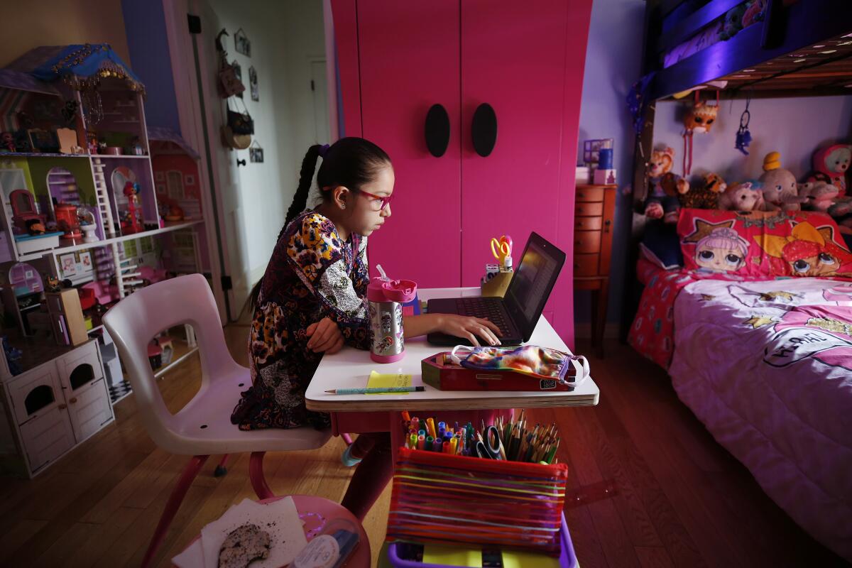 Student participates in an online class in her bedroom during remote learning lessons at home in Boyle Heights.