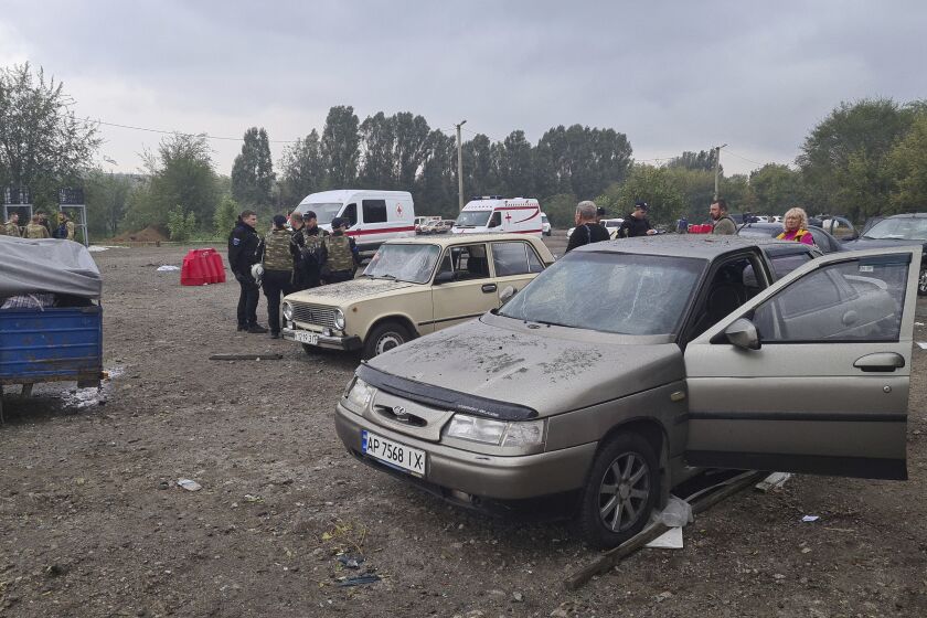 Police officers and medical workers work near damaged cars after a Russian rocket attack in Zaporizhzhia, Ukraine, Friday, Sept. 30, 2022. A Russian strike on the Ukrainian city of Zaporizhzhia killed at least 23 people and wounded dozens, an official said Friday, just hours before Moscow planned to annex more of Ukraine in an escalation of the seven-month war. (AP Photo/Viacheslav Tverdokhlib)