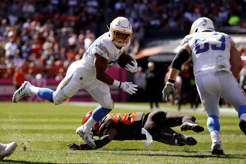 Los Angeles Chargers running back Austin Ekeler (30) breaks a tackle by Cleveland Browns safety Grant Delpit (22) during an NFL football game, Sunday, Oct. 9, 2022, in Cleveland. (AP Photo/Kirk Irwin)