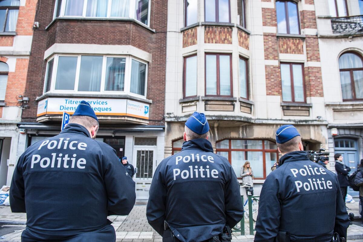 Three police officers stand guard in the Meiser neighborhood in Schaerbeek during an anti-terrorist operation searching for suspects of bombings in Brussels.