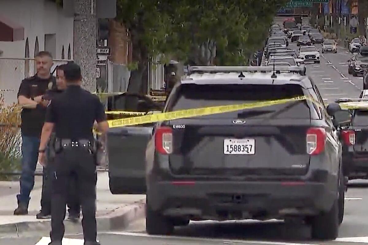 Three men stand near a sidewalk at left and next to a police SUV at the center. "Do not cross" tape is pulled across