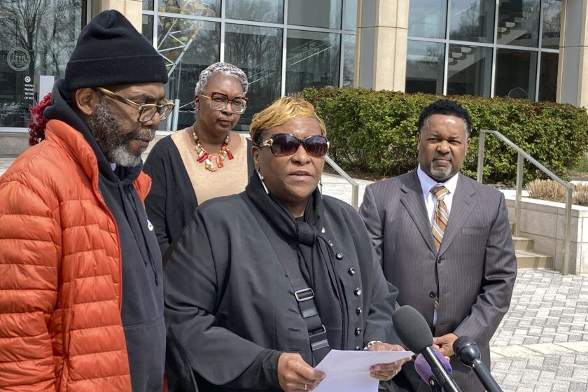 Timothy McCree Johnson's parents Melissa Johnson, center, and Timothy Walker, left, address reporters along with attorney Carl Crews, right, outside Fairfax County Police headquarters, Wednesday, March 22, 2023, in Fairfax, Va., after viewing police body camera video of their son's shooting death at the hands of police last month outside Tysons Corner Center shopping mall. (AP Photo/Matthew Barakat)
