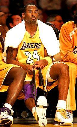 Kobe Bryant stretches his sprained ankle in the first half .