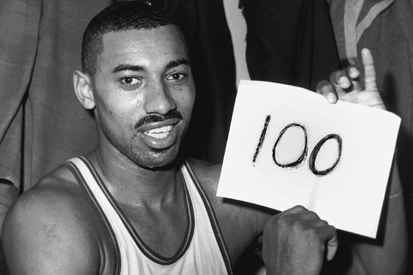 Wilt Chamberlain, of the Philadelphia Warriors, holds a sign reading "100" after he scored 100 points