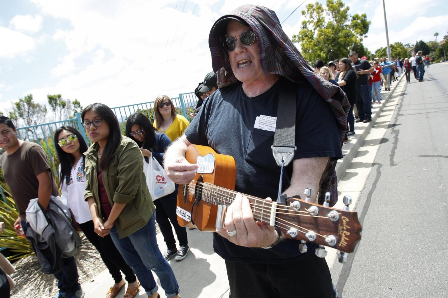 Bernie Sanders supporter Clay Mitchell sings his song called "Enough is Enough" as he and other people wait in line to see Democratic presidential candidate Bernie Sanders.