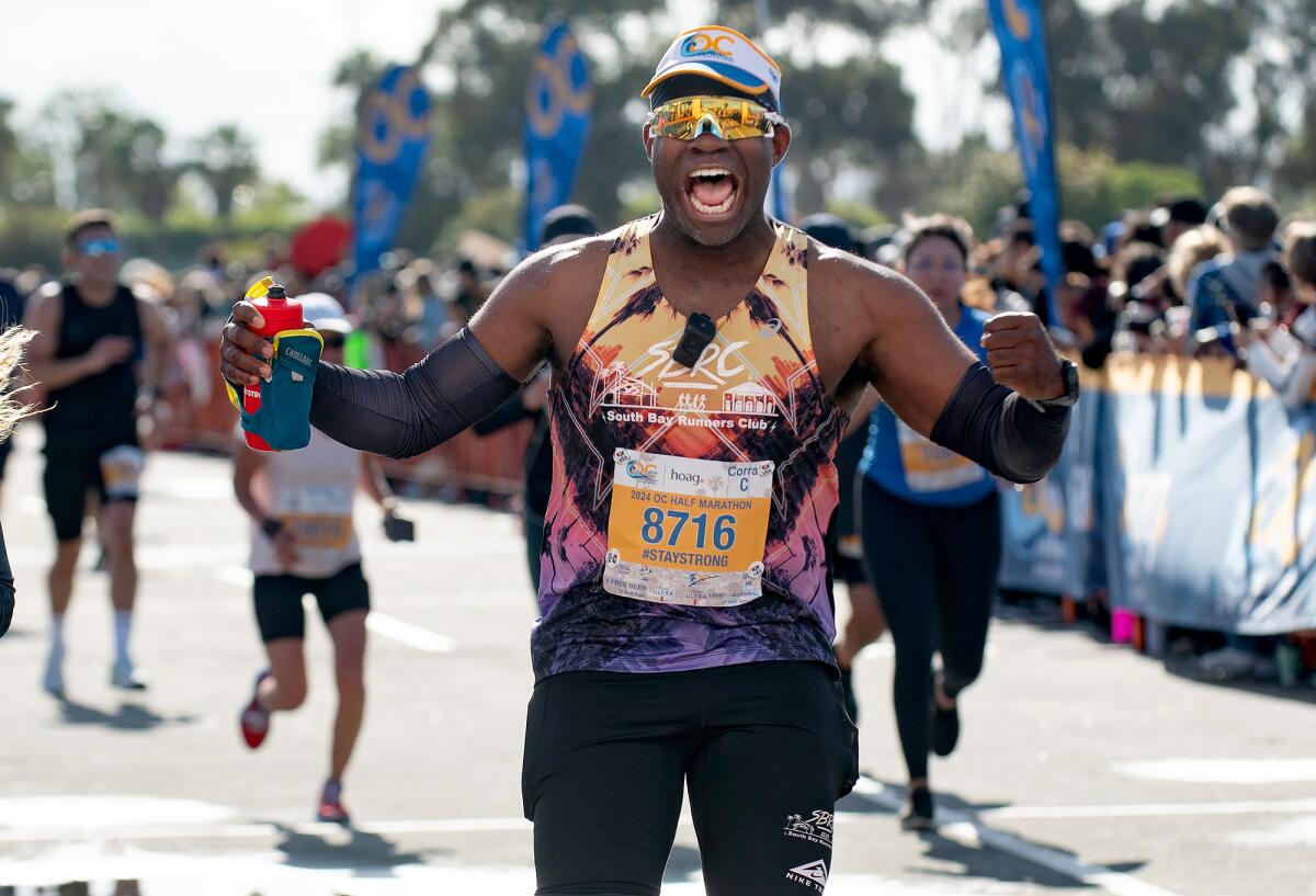 Maurice Washington pumps his fists as he approaches the finish line of the Orange County Half Marathon.