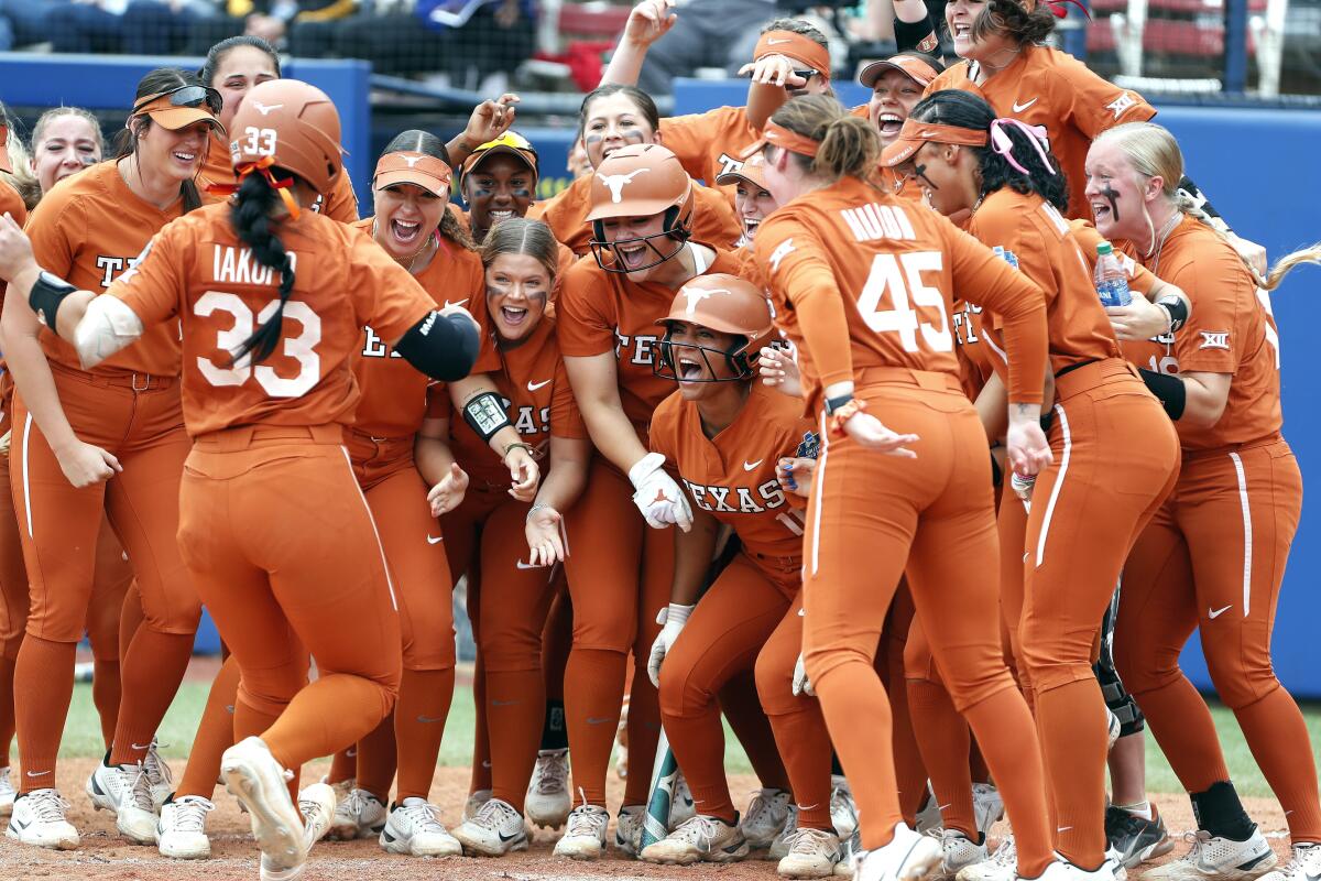 Texas catcher Mary Iakopo is greeted by her team at home plate after hitting a home run.