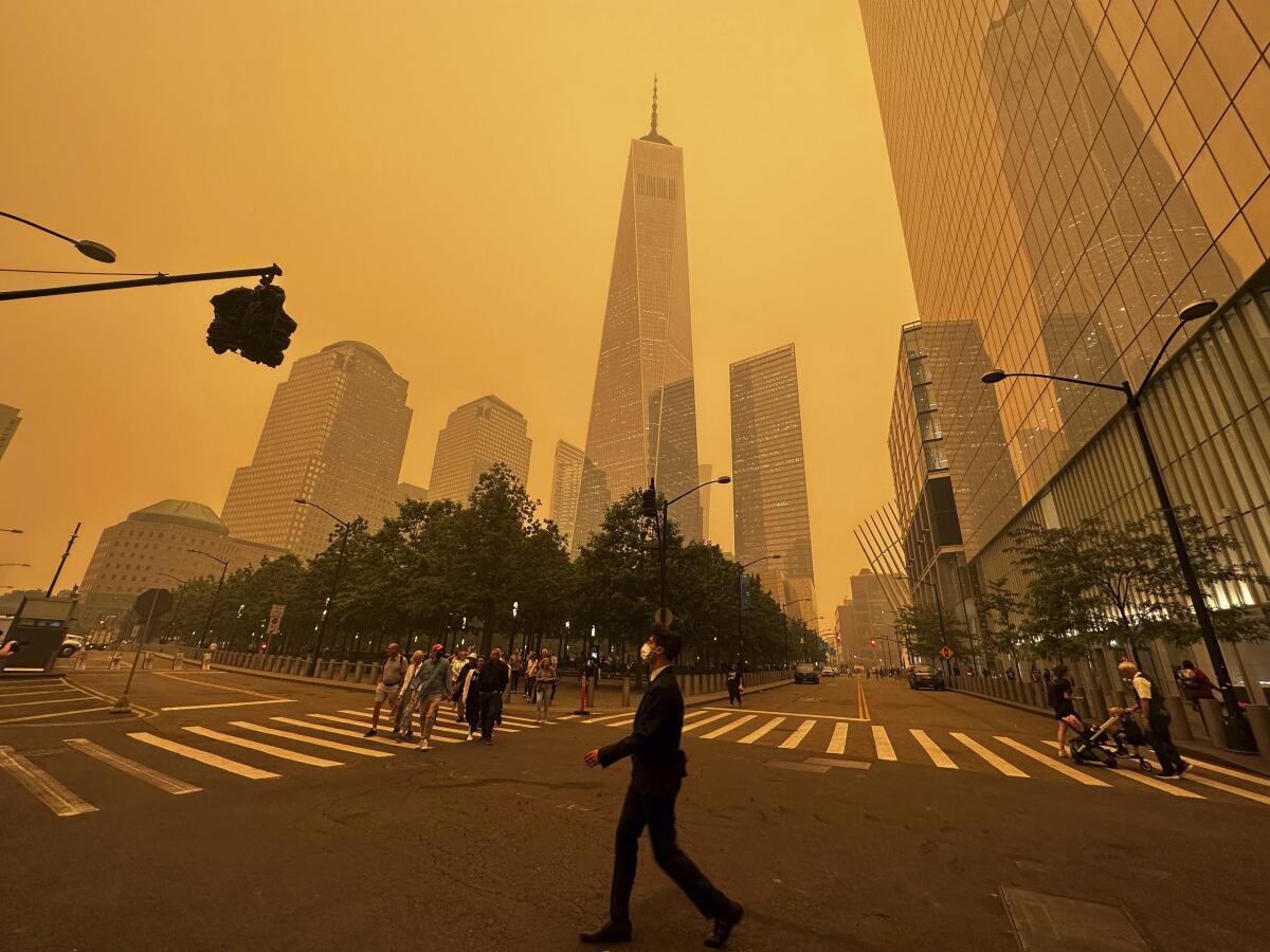 Pedestrians pass One World Trade Center, center, on Wednesday as the air is filled with smoke from wildfires in Canada.