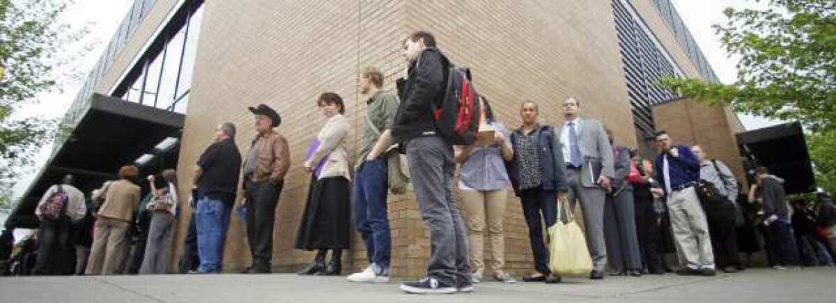 Job seekers wait in line during a job fair in Portland, Ore., in April.