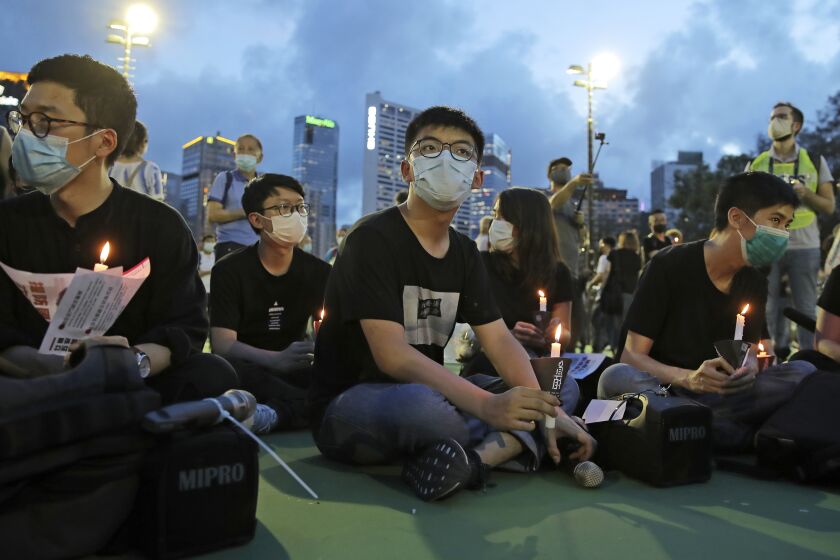 In this June 4, 2020, photo, democracy activist Joshua Wong, center, and Nathan Law, left, hold candles during a vigil to remember the victims of the 1989 Tiananmen Square Massacre at Victoria Park in Hong Kong. Wong will face an additional 10 months in jail for participating in an unauthorized Tiananmen vigil held last year to commemorate the 1989 crackdown on protesters in Beijing, as Hong Kong authorities continue tightening control over dissent in the city. (AP Photo/Kin Cheung)