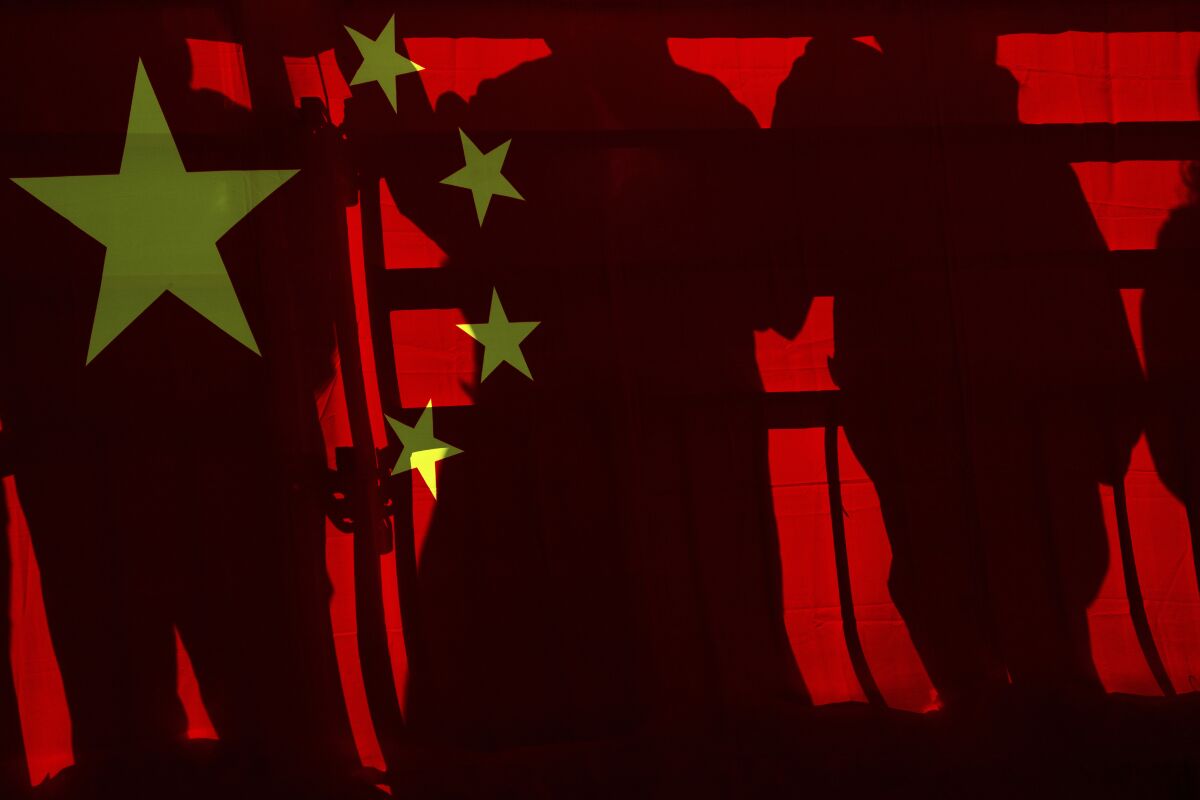 Spectators cast shadows on a Chinese national flag at a viewing platform during the men's and women's Alpine downhill at the 2022 Winter Paralympics, Saturday, March 5, 2022, in the Yanqing district of Beijing. (AP Photo/Andy Wong)