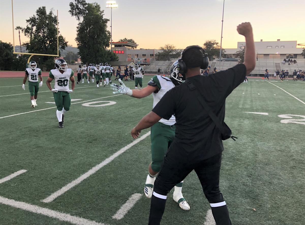 A Dorsey assistant coach greets players coming off the field after a defensive stop against Santa Monica on Friday night.