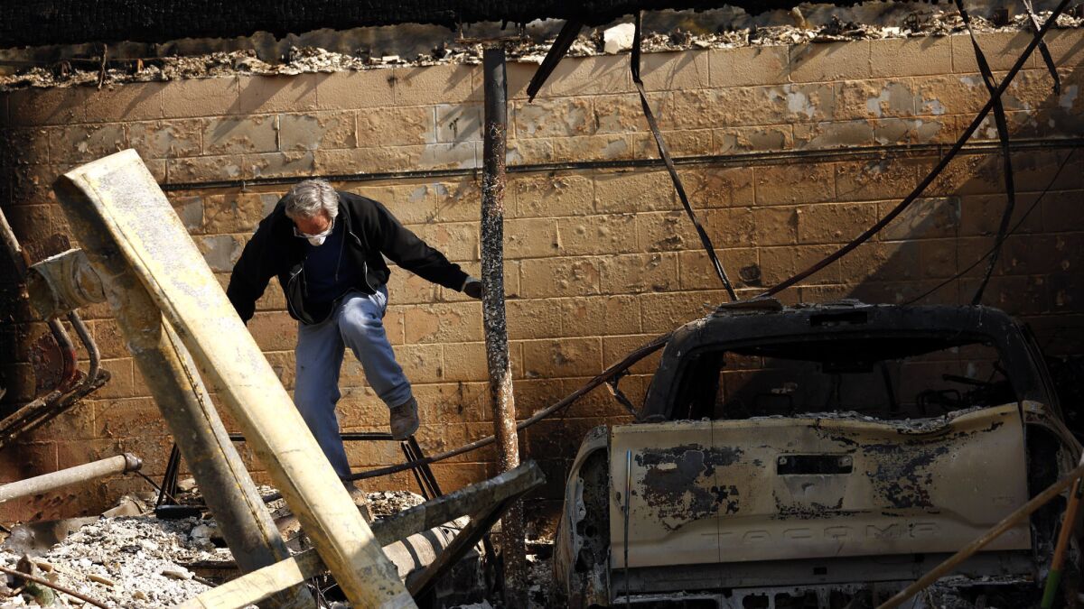 Bruce Costello, 62, walks through the rubble of his Wikiup home on Monday after it was destroyed in the wildfires.