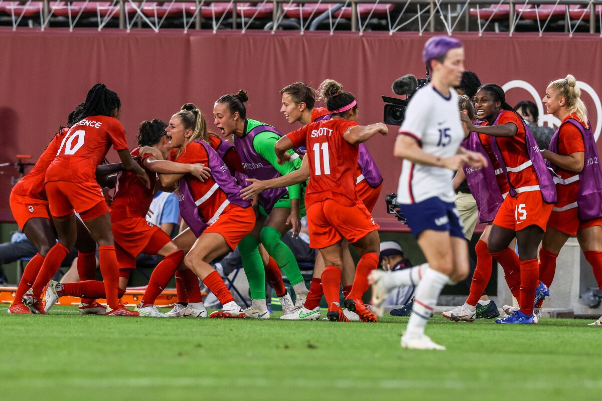 Canada players swarm midfielder Jessie Fleming after she scored on a penalty kick against the U.S. on Monday.