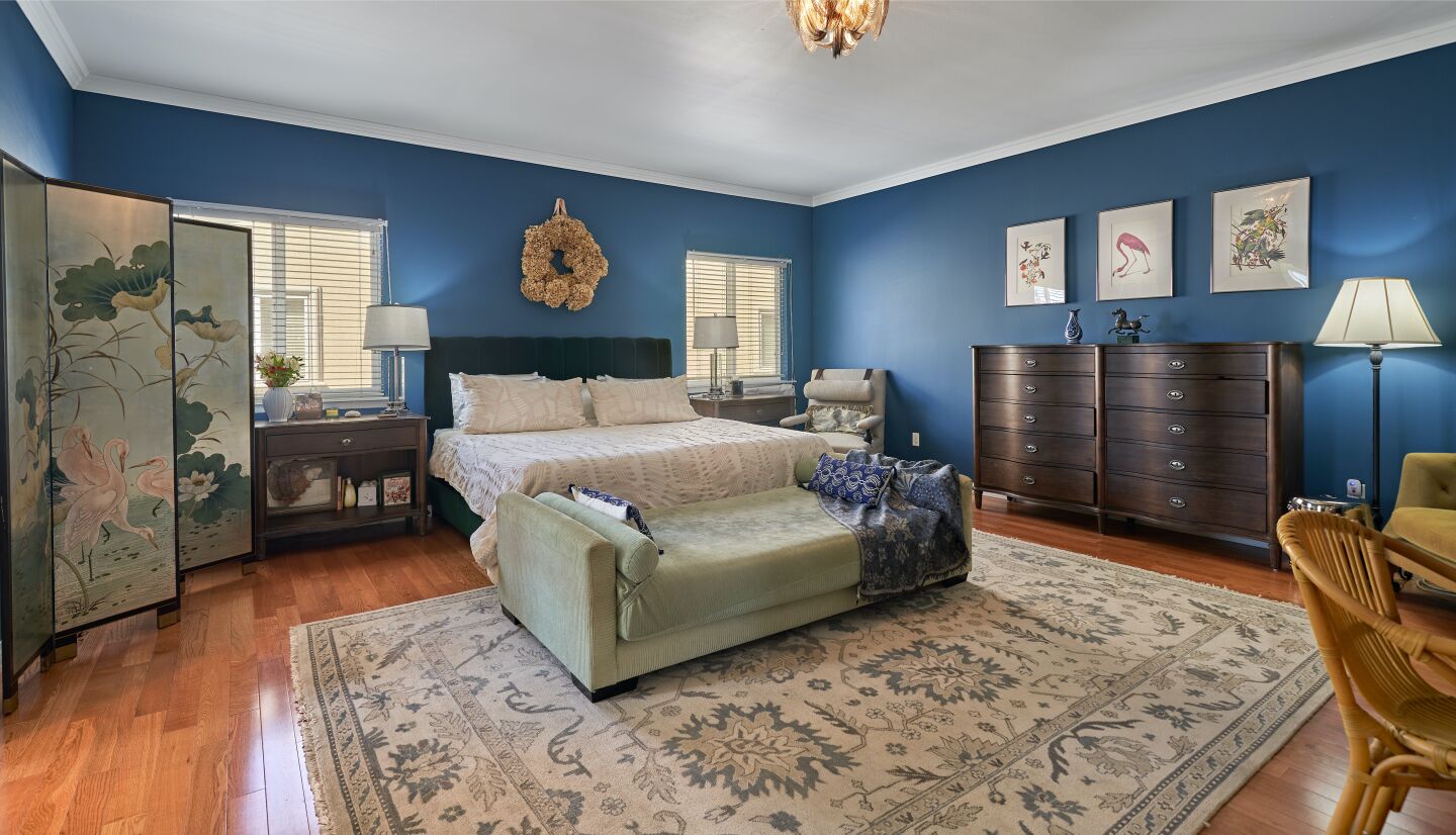 The primary bedroom is furnished and painted blue with a big rug and a window.