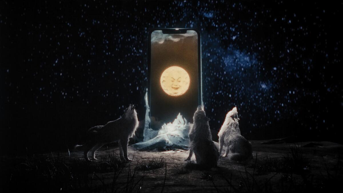 Wolves howl around a giant cell phone.