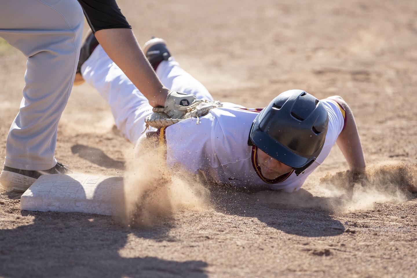 Estancia's Garrett Palme dives back to the bag on a pick-off attempt by Costa Mesa's Omar Munoz in an Orange Coast League game on Wednesday.