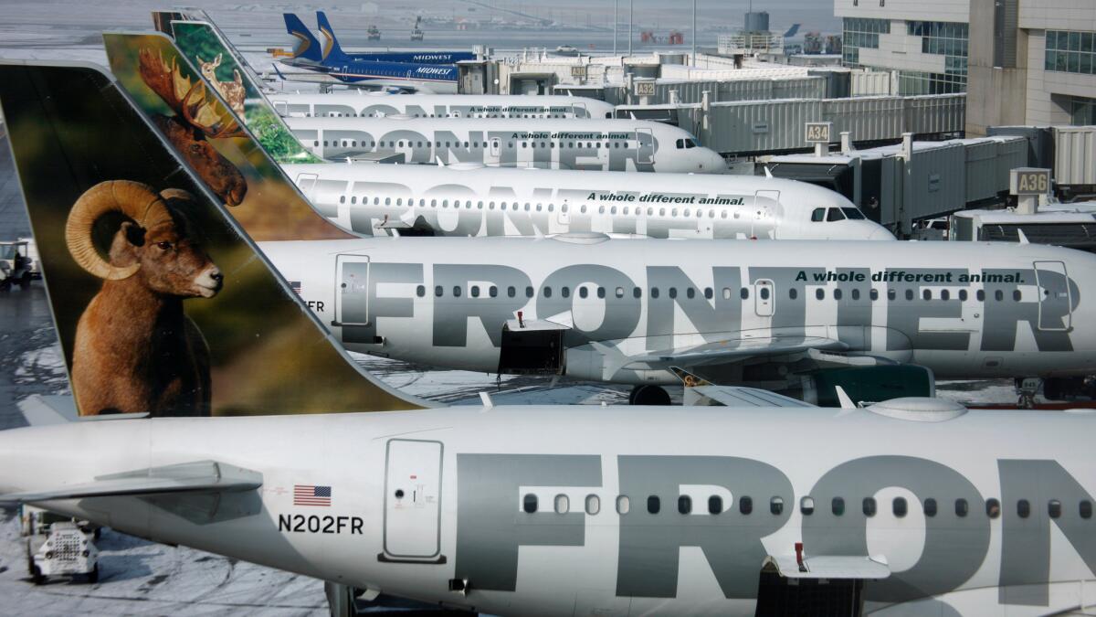 Frontier Airlines planes sit in a row at Denver International Airport.