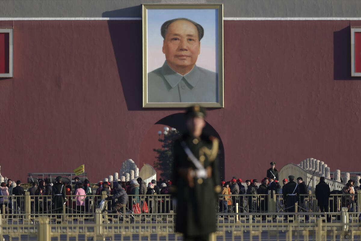 Chinese paramilitary policemen stand watch over visitors in March near a portrait of Mao Tse-tung on Tiananmen Square in Beijing.