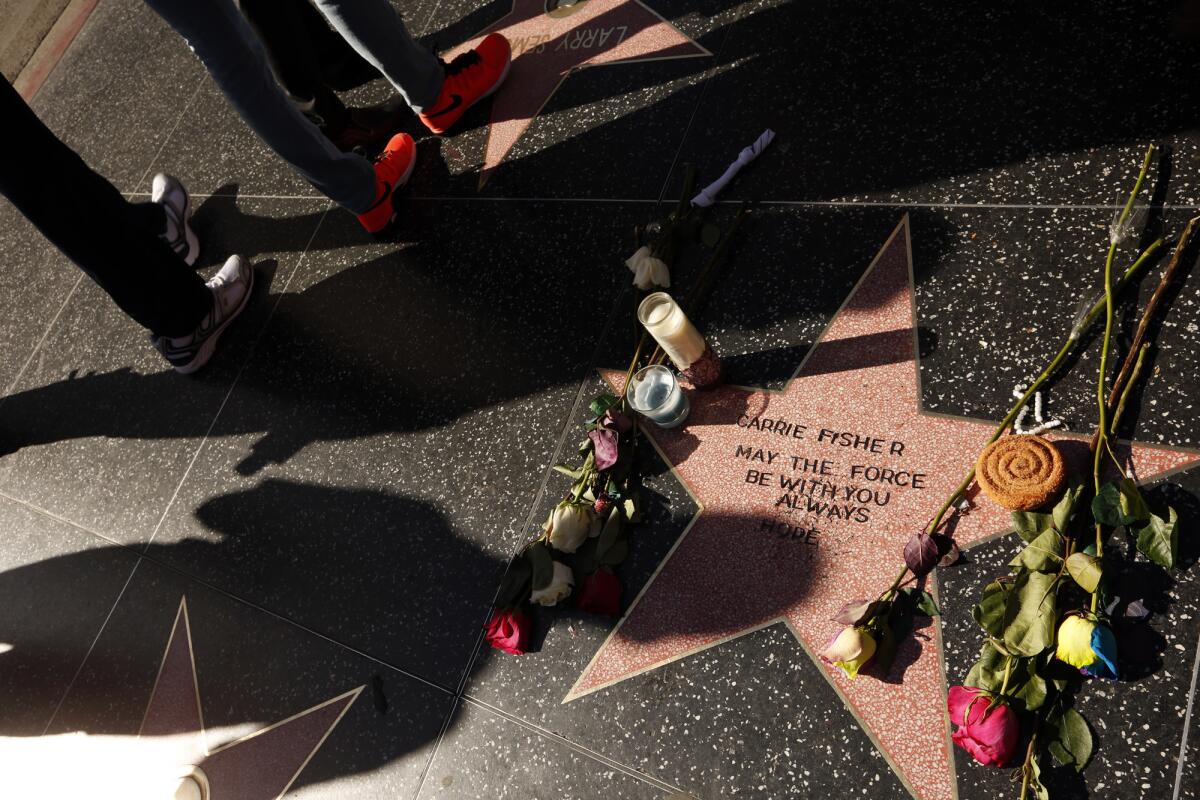 People observe a star that is dedicated to the memory of "Star Wars" actress Carrie Fisher on the Hollywood Walk of Fame.