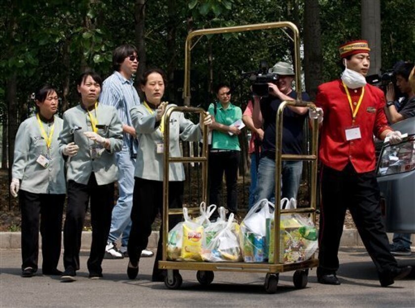 Hotel workers wearing gloves as a precaution against swine flu carry a cart loaded with foods to a sealed-off hotel where Mexican travelers are being held under quarantine in Beijing, China, Monday, May 4, 2009. China on Monday denied discriminating against Mexicans in its fight against swine flu after the Latin American country complained that more than 70 Mexican travelers have been quarantined even though some are apparently not at risk for the virus. (AP Photo/Andy Wong)