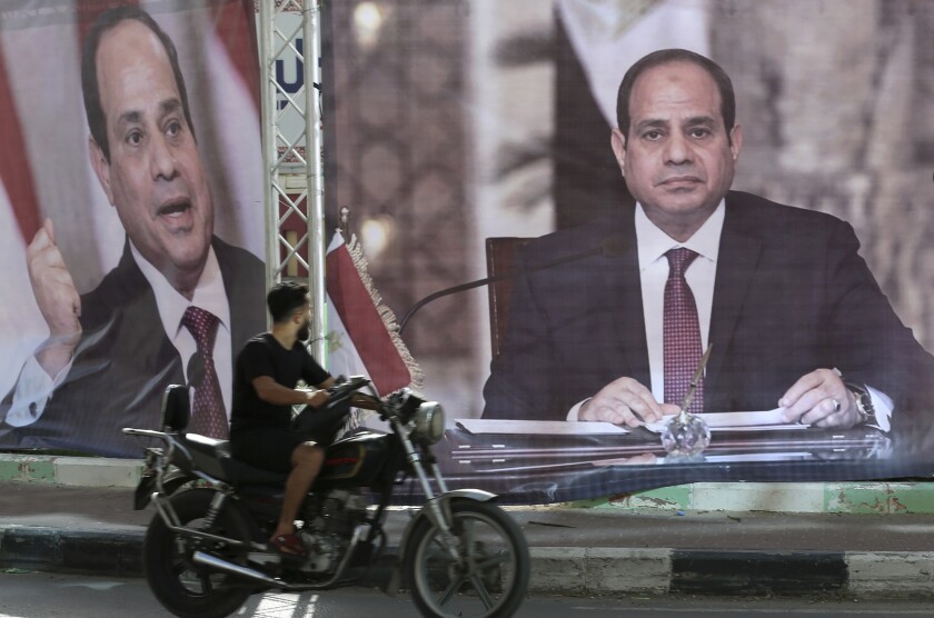 A motorcyclist passes large posters of Egyptian President Abdel Fattah Sisi displayed in Gaza City.