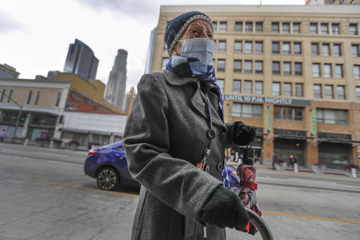 Juanita Aviles, 98, on her way to home on Broadway in downtown Los Angeles. Mayor Eric Garcetti ordered the closure of bars and nightclubs and ordered restaurants to halt dine-in service until March 31.