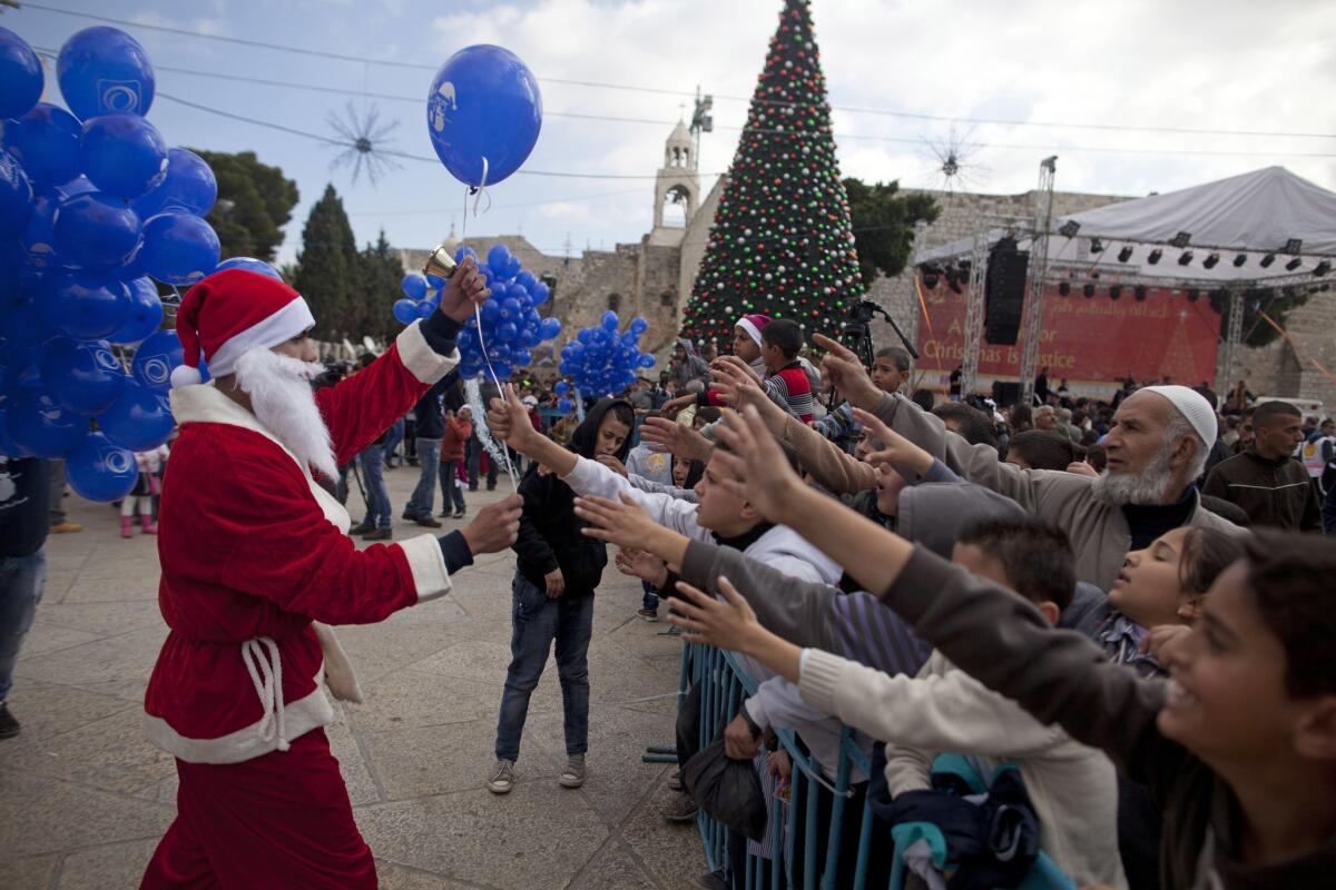 A Palestinian man dressed in a Santa Claus costume gives out balloons outside the Church of the Nativity in Bethlehem on Dec. 24.