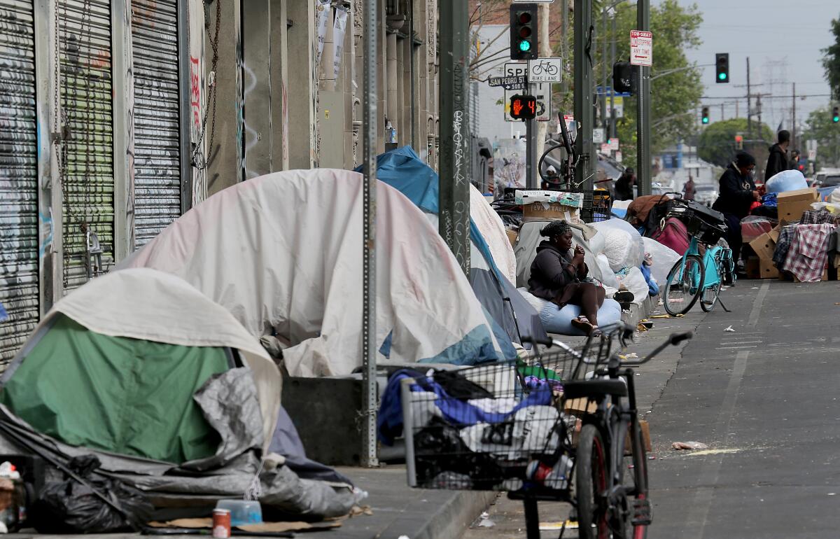 People, tents and piles of belongings on a city sidewalk