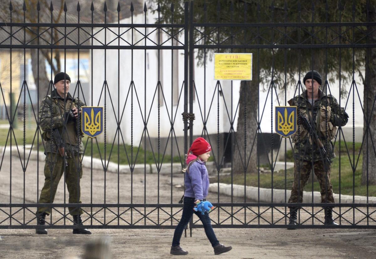 A girl passes in front of Ukrainian soldiers guarding the entrance to a Ukrainian naval base near Simferopol.